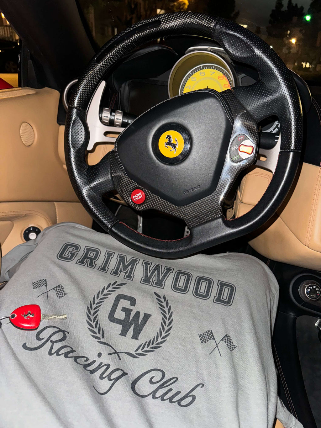 Steering wheel with a Ferrari logo and a shirt with 'Grimwood Racing Club' text inside a car.