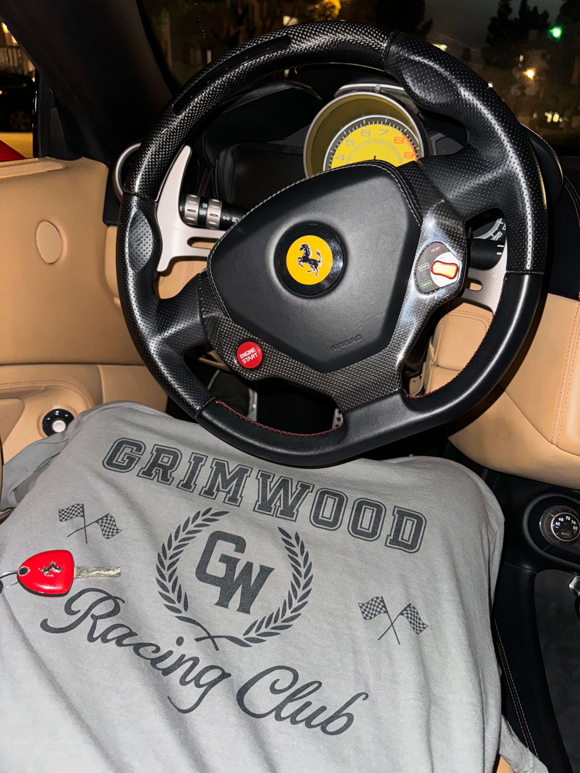 Steering wheel with a Ferrari logo and a shirt with 'Grimwood Racing Club' text inside a car.