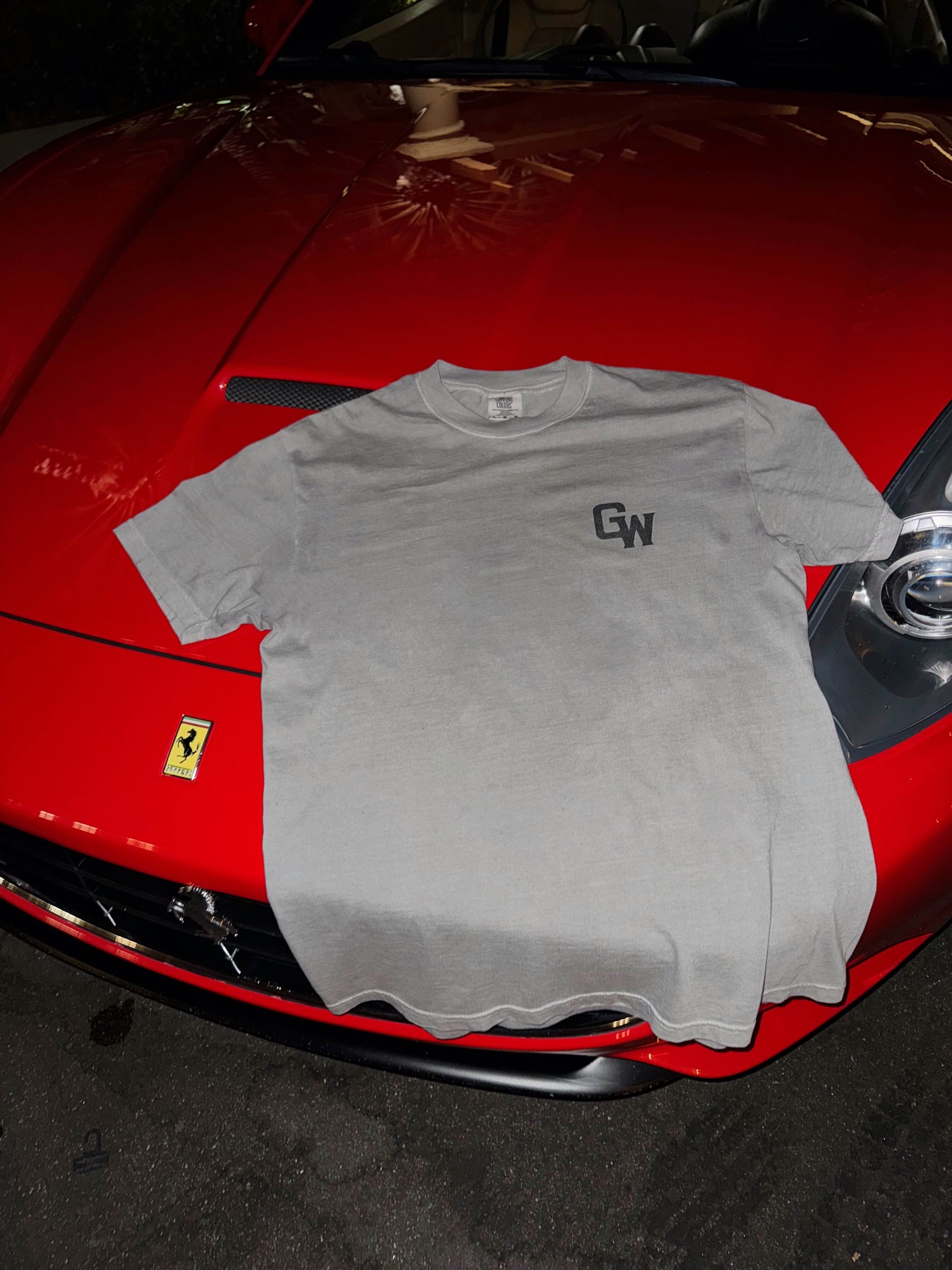 Gray t-shirt with 'GW' logo on a ferrari red car